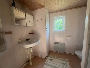 A small bathroom with a white sink, a mirror above it, a window, and a toilet. - 2 Person Holiday Home in Burseryd (Burseryd)