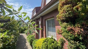 A brick house with a window, a pathway, and various plants. - Reihenhaus, Dornumersiel (Dornum)