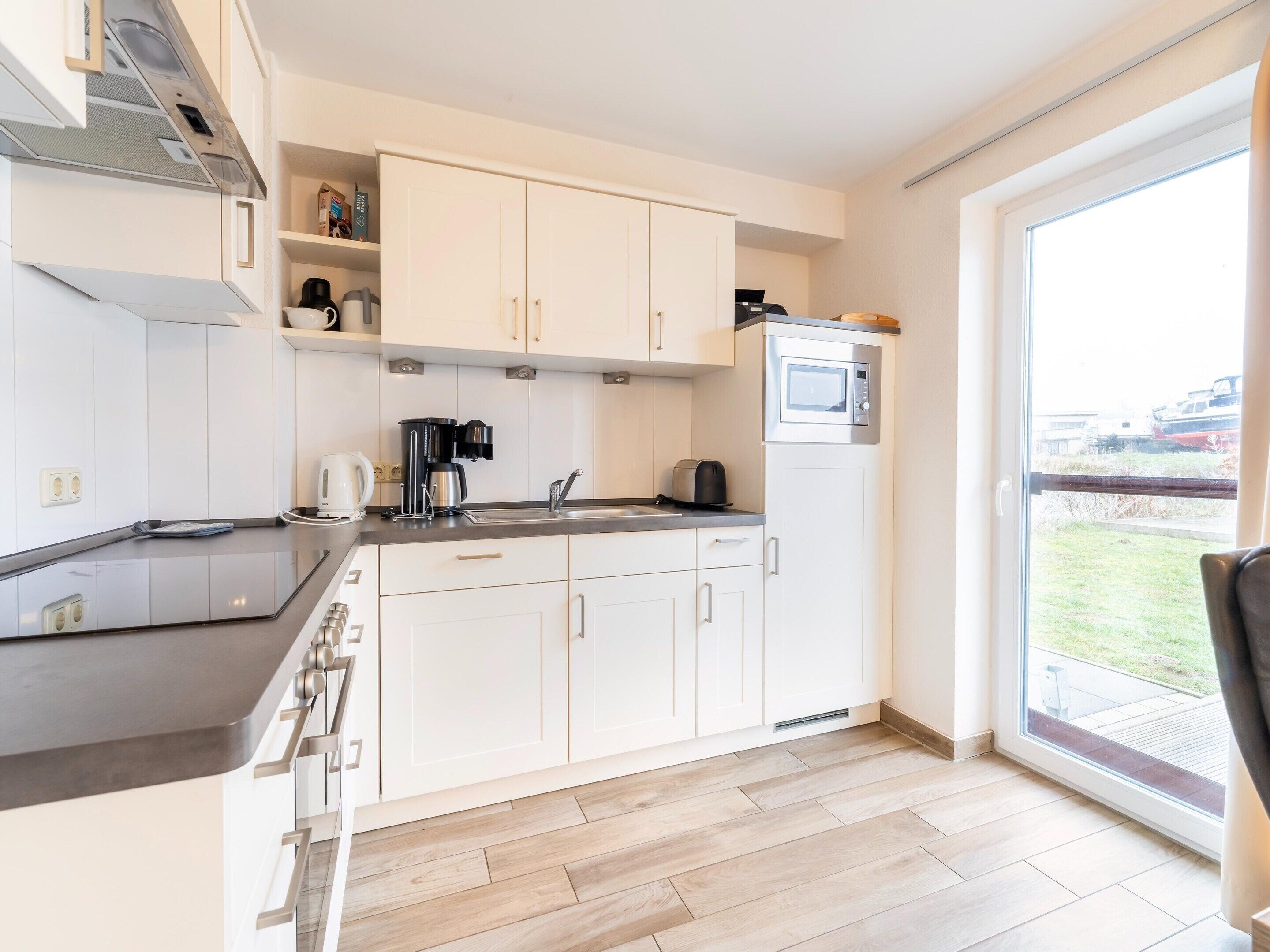 Een moderne keuken met witte kasten, een zwart aanrecht en een ingebouwde magnetron.