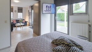 A bedroom with a bed, a TV mounted on the wall, and a window with a view of the outside. - Spacious Holiday Home With Sauna Near Beach (Wemeldinge)