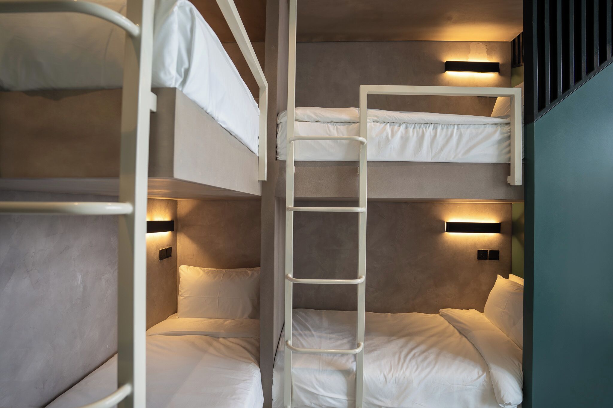 Une chambre avec un lit superposé, une échelle, deux tables de chevet et des lampes fixées au mur.