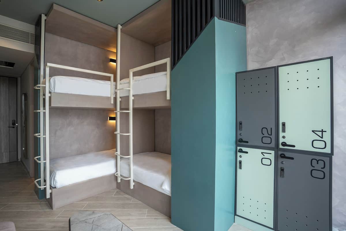 A compact room with bunk beds, a small seating area, and a wardrobe with numbered compartments.