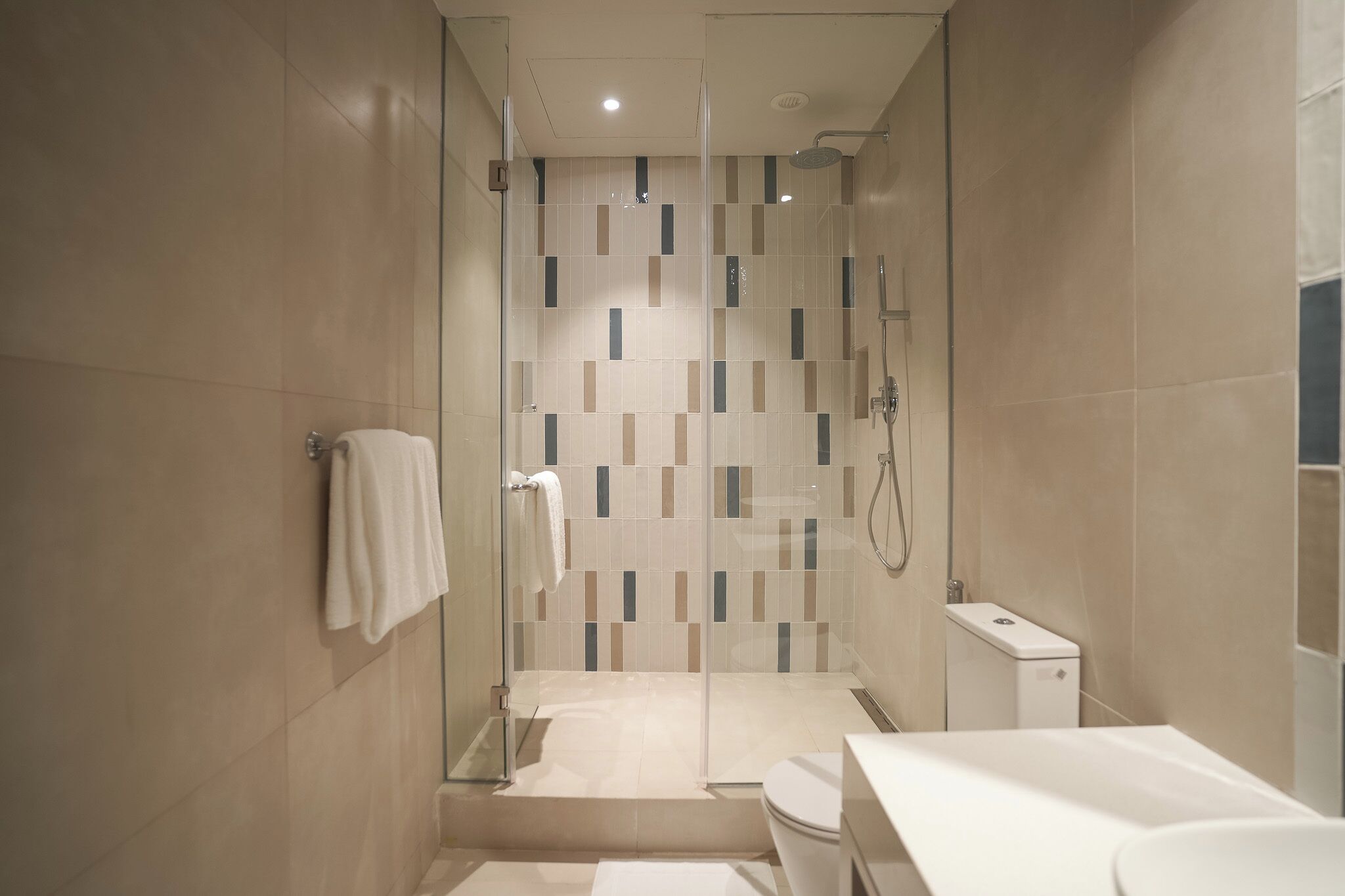 A modern bathroom with a glass-enclosed shower, a toilet, and a sink.