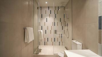 A modern bathroom with a glass-enclosed shower, a toilet, and a sink.