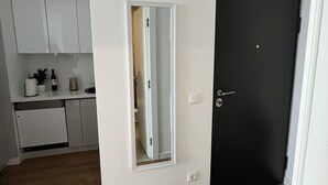 Una cocina moderna con armarios blancos, una puerta negra y un espejo en la pared.