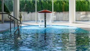 A swimming pool with a water fountain, surrounded by large windows and a concrete wall. - Ideale Familienwohnung in der Natur (Mirow)