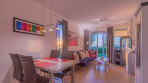 Ein modernes Wohnzimmer mit Essbereich, einer Sofagarnitur und Blick ins Freie.