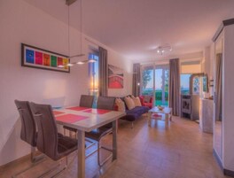 Una sala de estar moderna con comedor, un conjunto de sofás y vistas al exterior.