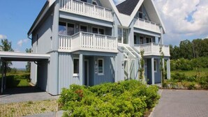 Ein zweistöckiges Haus mit einem Balkon im ersten Stock und einer überdachten Veranda im Erdgeschoss.