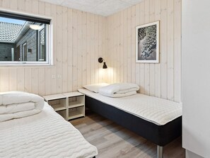 Quarto com duas camas, uma janela, luminária fixada na parede e um quadro emoldurado.
