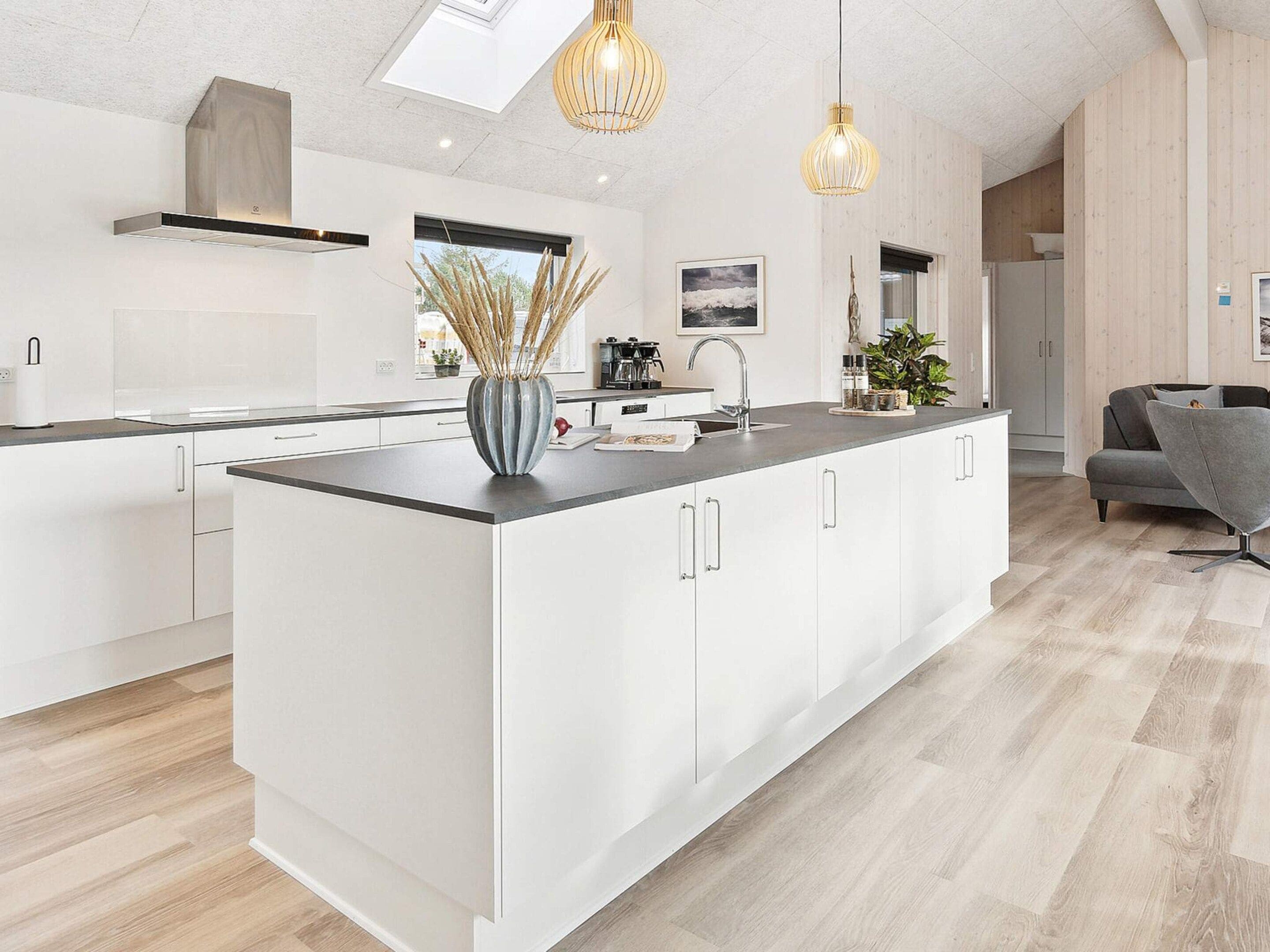 A modern kitchen with a central island, white cabinetry, and a skylight.