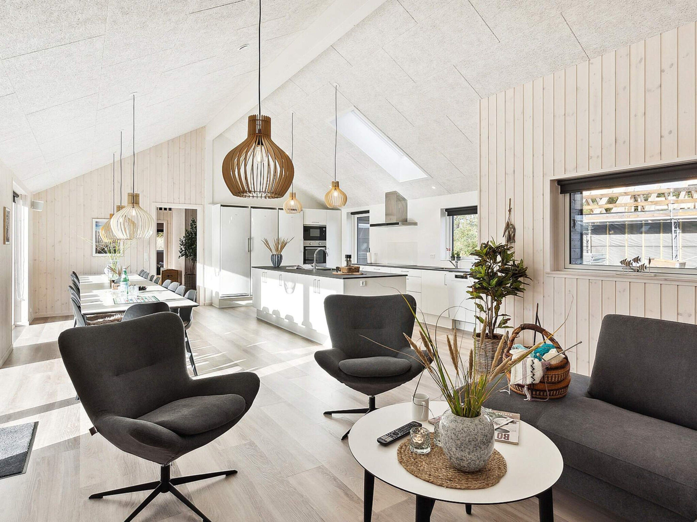 A modern interior with a dining area, two sofas, a coffee table, and a kitchen in the background.
