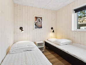 A room with two beds, a small table, and a window.