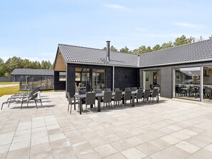 A modern building with a patio area featuring outdoor seating and a covered section.