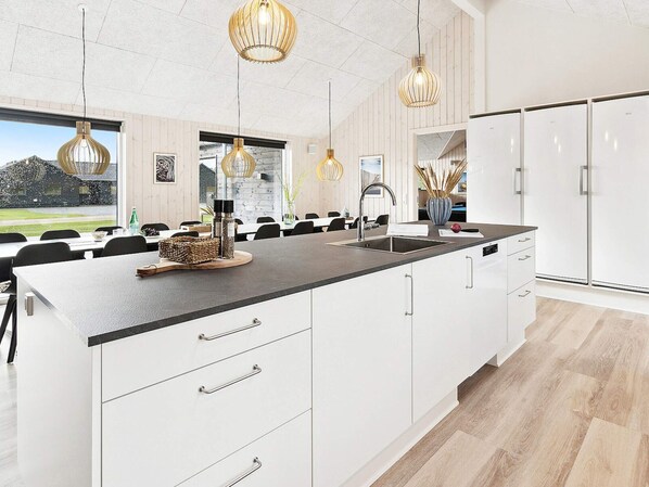 A modern kitchen with a central island, white cabinetry, and pendant lighting.
