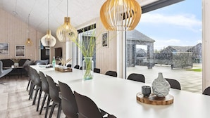 A modern dining area with a long table, chairs, and pendant lighting. - 5 Star Holiday Home in Romo (Rømø)