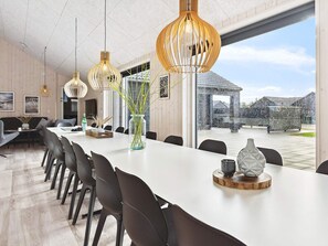 A modern dining area with a long table, chairs, and pendant lighting. - 5 Star Holiday Home in Romo (Rømø)