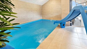 An indoor swimming pool with a slide, tiled walls, and a plant. - 5 Star Holiday Home in Romo (Rømø)