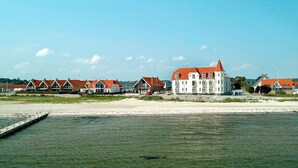 A coastal building complex with multiple structures, a pier extending into the water, and a clear sky. - 4 Person Holiday Home on a Holiday Park in Hejls (Hejls)