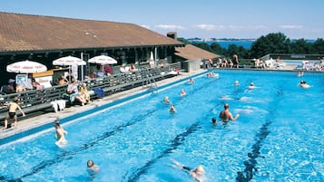 Piscina com várias pistas, espectadores e guarda-sóis.