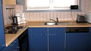 Een kleine keuken met een fornuis, spoelbak en broodrooster.