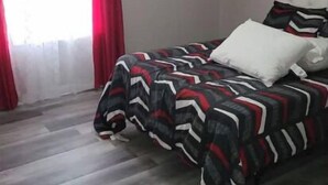 Un dormitorio con cama, ventilador de techo y ventana con cortinas.