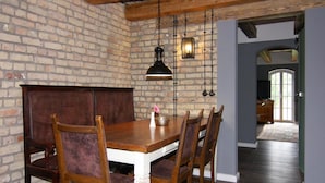 A dining area with a wooden table and chairs, a brick wall, and hanging lights. - Ferienhaus Birgit, Wendorf (Kuhlen-Wendorf)