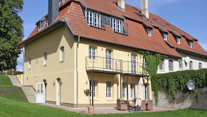 A two-story building with a red-tiled roof, multiple windows, and a balcony with outdoor furniture. - Ferienhaus Birgit, Wendorf (Kuhlen-Wendorf)