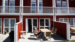 Ein rotes Gebäude mit weißem Zierfachwerk, das einen Balkon mit weißen Geländern und zahlreiche Fenster aufweist.