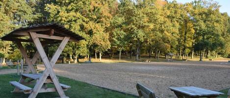A picnic area with wooden benches and a shelter, surrounded by trees.