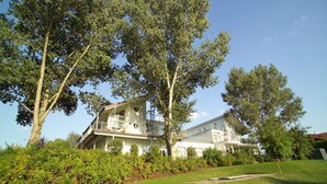 A two-story house with a balcony, surrounded by lush greenery and trees. - Elegant Eingerichtete Ferienwohnung (Mirow)