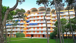 Een hotel met meerdere verdiepingen, balkons, een gazon en bomen.