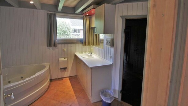 Une salle de bain avec une baignoire, un lavabo et une fenêtre.