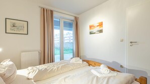 Una camera d'albergo con un letto, un termosifone, una finestra con tende e una porta.