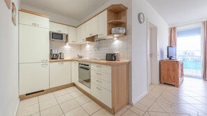 Una cucina compatta con mobili bianchi, un forno a microonde, un fornello e un piano di lavoro in legno.