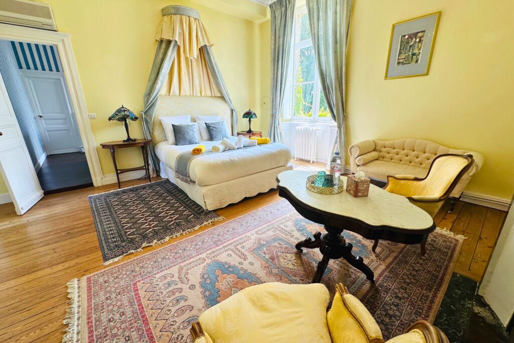 A bedroom with a bed, bedside table, chair, and a window with curtains.