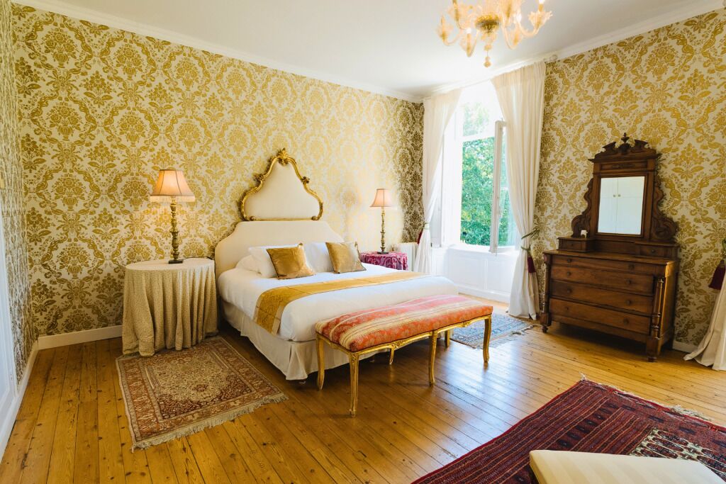A bedroom with a bed, bedside tables, a dresser, and a window with curtains.