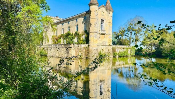 Un edificio histórico con una torre, rodeado de agua y vegetación.