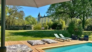 Zona de piscina con sillas de descanso y una terraza de madera.