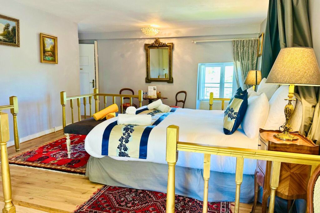 A hotel room with a bed, a nightstand, a lamp, a mirror, and a window.