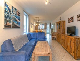 Una sala de estar moderna con un sofá azul, una mesa de centro de madera y un televisor sobre un mueble de madera.