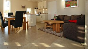 A modern living room with a wooden coffee table, a sofa, and a dining area with chairs and a table.