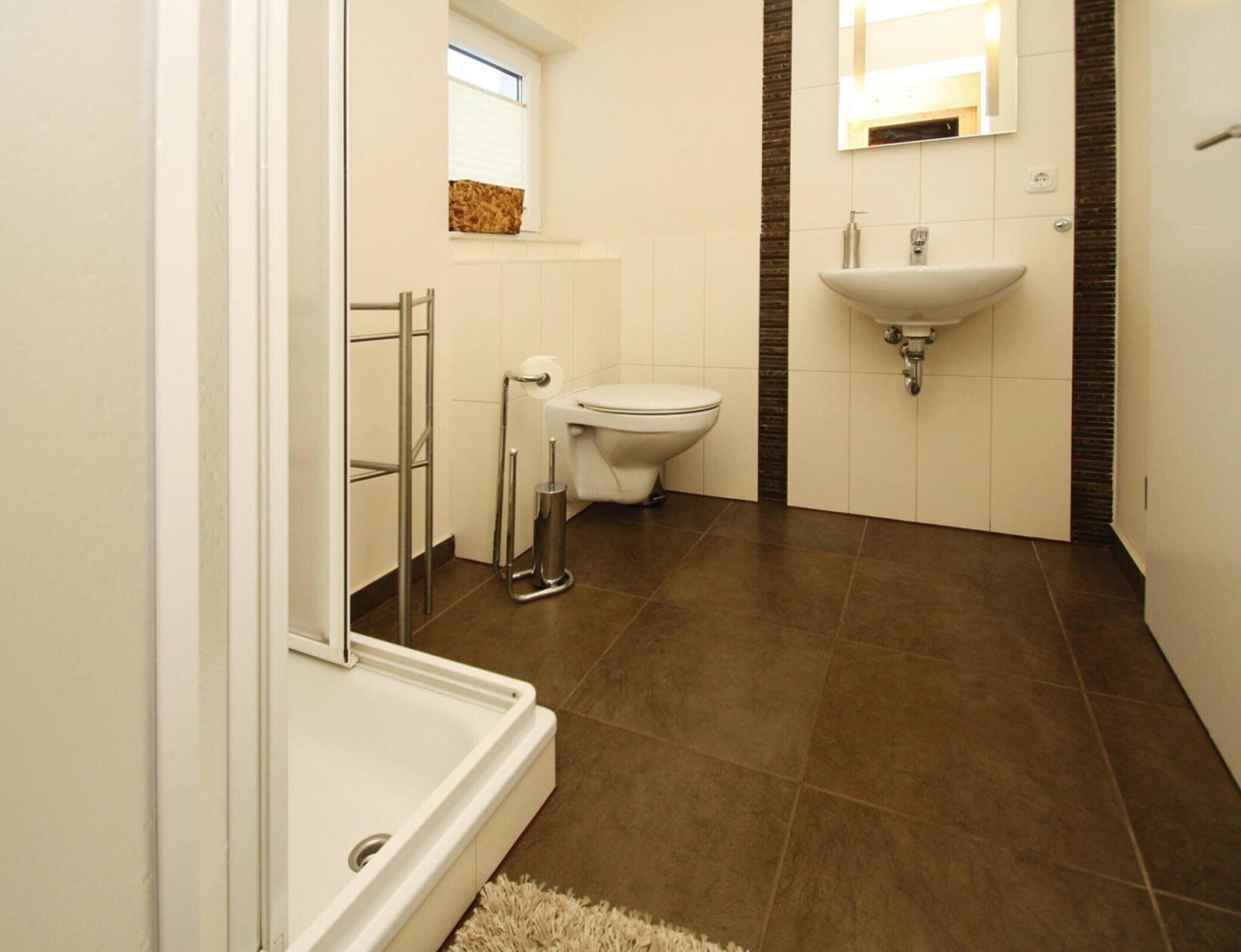 A modern bathroom with a shower, toilet, and sink.