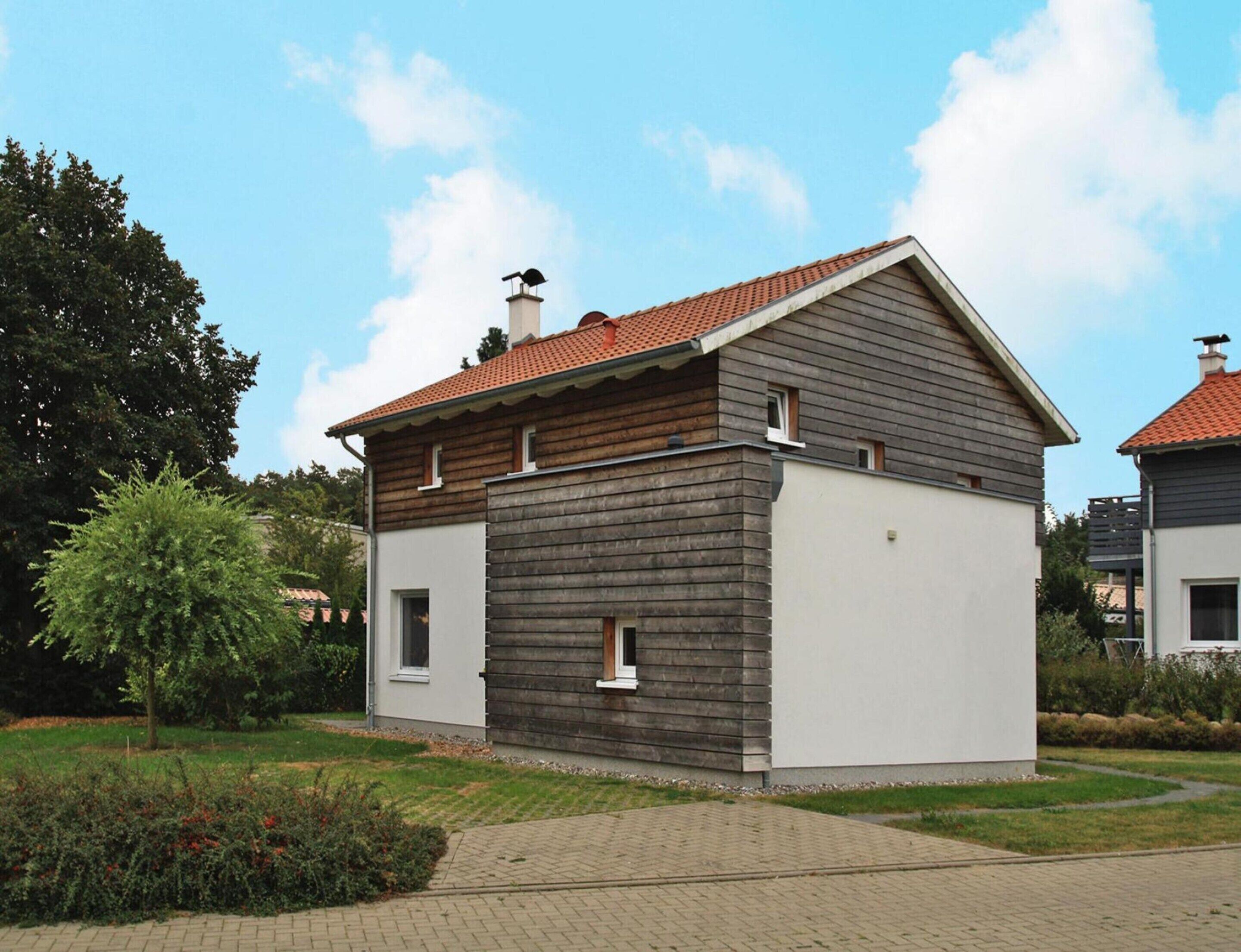 A modern two-story house with a sloped roof and a chimney.