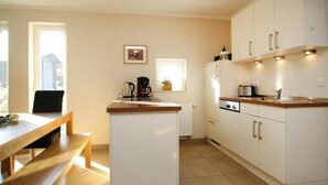 A kitchen with white cabinets, a wooden countertop, a built-in oven, and a dining area with a bench.