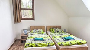 Une chambre avec deux lits simples, une table de chevet, une fenêtre et un plancher en bois.