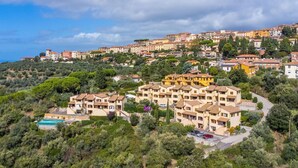 Una zona residencial en una colina con casas escalonadas, una piscina y un camino sinuoso.