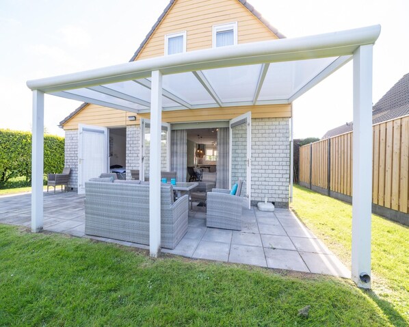 A covered patio area with wicker furniture and a view of the house's interior. - Holiday Home With Sauna Near Beach (Wemeldinge)