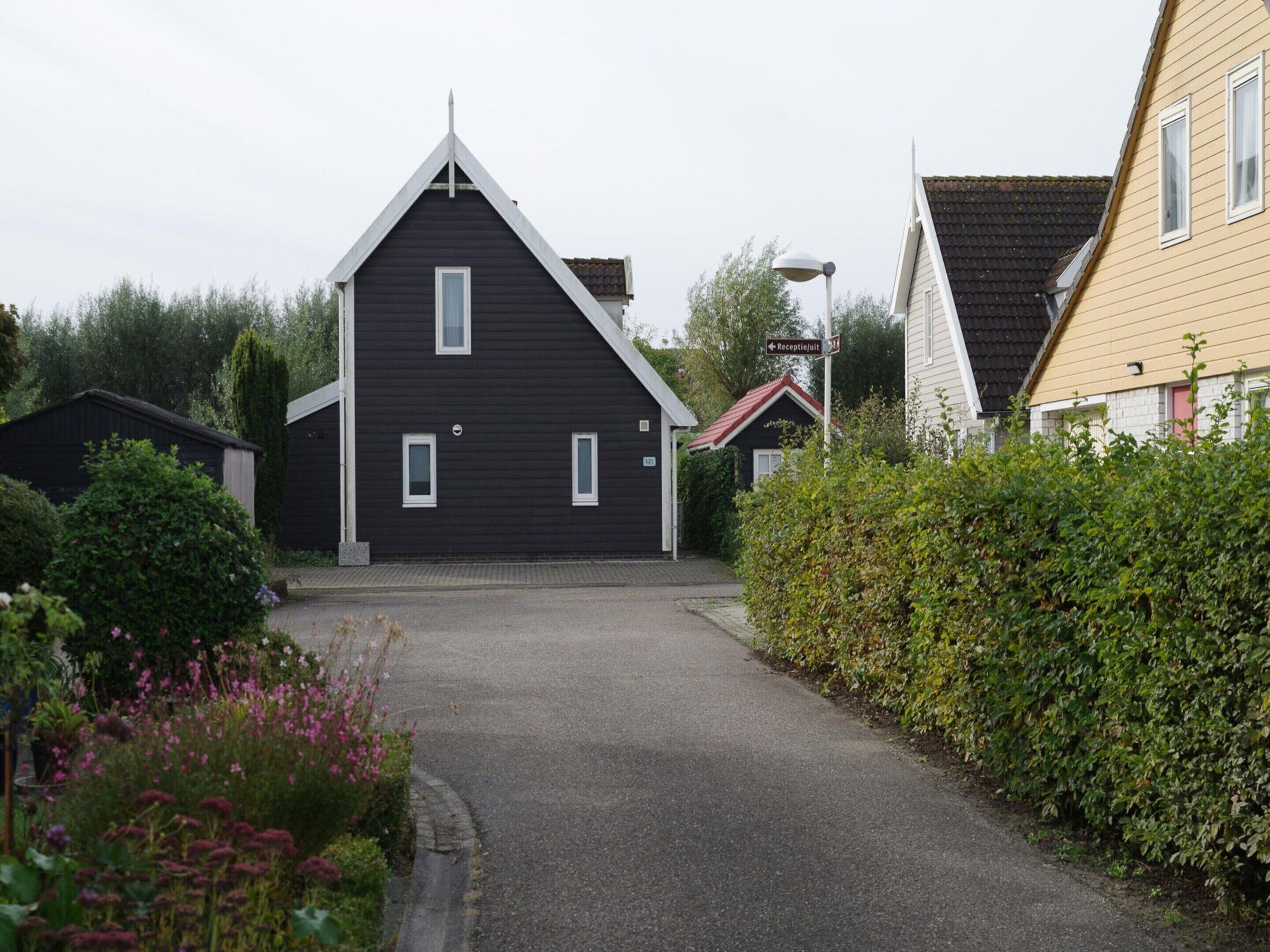 A black building with a triangular roof and a small porch.