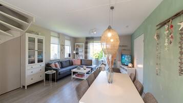 A spacious living area with a dining table, sofa, and a television.